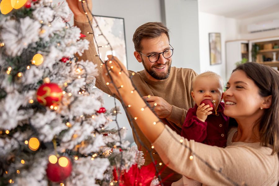 family putting lights on tree together